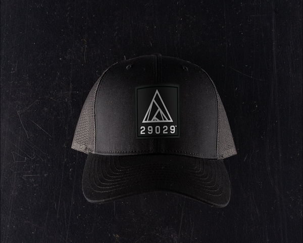 Grey trucker hat featuring a PVC patch on the front that is black with a white 29029 lockup logo.