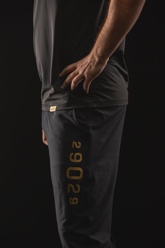 Men's joggers in black with a gold 29029 numeric logo down the left leg on the side. 